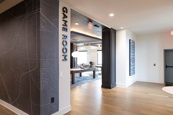 A hallway with a game room sign on the wall.